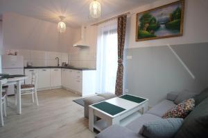 a living room with a couch and a table and a kitchen at Apartamenty Magiczny Kącik in Poronin