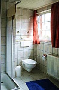 een badkamer met een toilet, een bad en een raam bij Pension Fröhlich in Gager