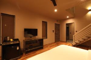 um quarto com uma cama, uma televisão e uma escada em Isola Luxury Farm Suites em Nashik