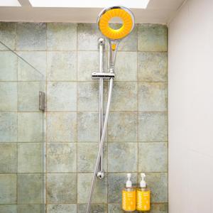 a shower with an orange shower head in a bathroom at Bloom Boutique - Bandra in Mumbai