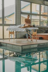 une femme assise sur un lit à côté d'une piscine dans l'établissement Les Jardins de Nicole, à La Plaine des Cafres