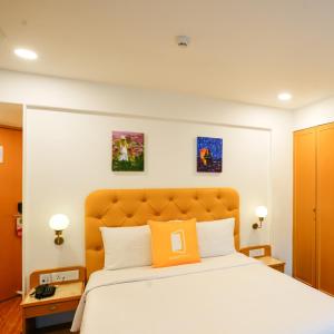 Dormitorio con cama con almohada naranja en Bloom Boutique - Bandra, en Bombay