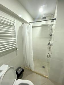 a white bathroom with a shower with a toilet at GSS - B Apartment in Tbilisi City