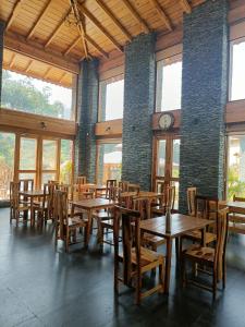 ein Restaurant mit Holztischen und -stühlen und einer Uhr in der Unterkunft Osho Himalayas Wellness Resort in Kangra