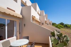 ein weißes Haus mit einem Tisch und Kaktus in der Unterkunft Apartamentos Marcelino - Formentera Break in Es Pujols