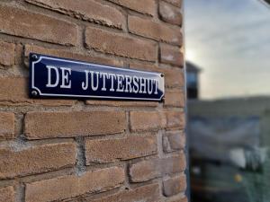 una señal azul en el costado de una pared de ladrillo en De Juttershut, en Egmond aan Zee