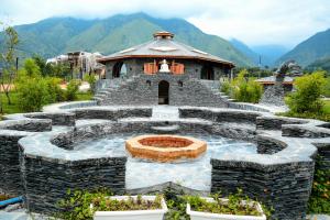 un edificio de piedra con una fuente en el medio en Osho Himalayas Wellness Resort en Kangra