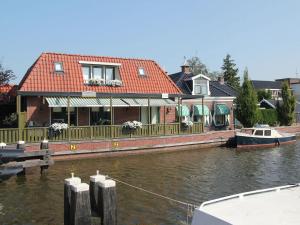 DelfstrahuizenにあるUnique Holiday Home with Terrace Barbecue Garden Furnitureの船が水上の家に停泊している