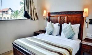 a bedroom with a large white bed and a window at FabHotel Prime Neelam The Glitz in Calangute