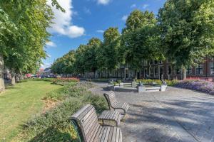 una fila de bancos en un parque con árboles y flores en Drie Wijzen, en Zierikzee