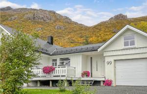 una casa blanca con garaje y montañas al fondo en Cozy Home In Straumsjen With Kitchen, en Straumsjøen