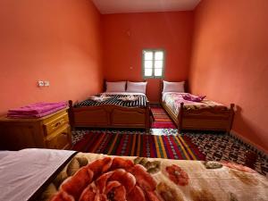 2 Betten in einem Zimmer mit orangefarbenen Wänden in der Unterkunft Hotel Izlane in Imilchil