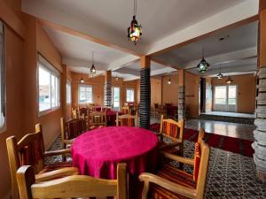 een eetkamer met een roze tafel en stoelen bij Hotel Izlane in Imilchil