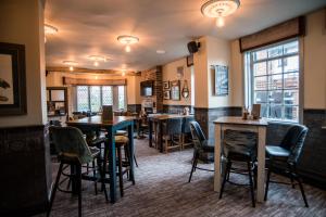 Cat & Lion Country Pub and Hotel في وارينغتون: وجود بار بالطاولات والكراسي في المطعم