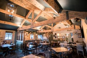 Cat & Lion Country Pub and Hotel في وارينغتون: غرفة طعام بها طاولات وكراسي وسقوف خشبية