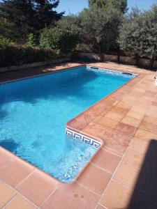 a swimming pool with blue water and a brick patio at Chalet entre parques naturales in Vallgorguina