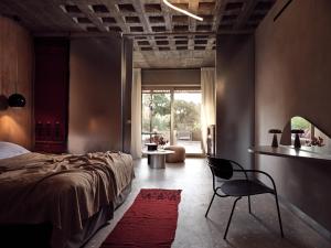 a bedroom with a bed and a chair in it at Ekies All Senses Resort, a Member of Design Hotels in Vourvourou