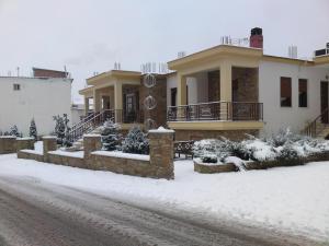 una casa con nieve en el suelo delante de ella en Evenos en Kato Loutraki