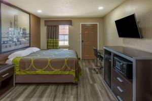 a hotel room with a bed and a flat screen tv at Super 8 by Wyndham Tulsa/Arpt/St Fairgrounds in Tulsa