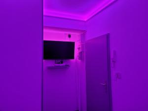 une chambre violette avec une télévision et une porte dans l'établissement Appart'Hôtel de la Gare - Cocooning, à Montbéliard