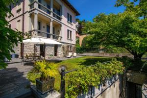 a building with an umbrella in front of a yard at Luxury Villa Como Lake View Private in Como