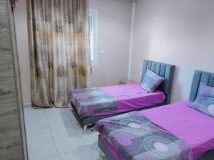 2 Betten in einem Zimmer mit rosa und lila Bettwäsche in der Unterkunft Family house in Ḩammām al Ghazzāz