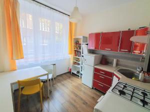 cocina con armarios rojos, mesa, mesa y sillas en Basic, quiet apartment close to Main Square, en Cracovia