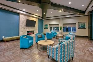 una sala de espera con sillas azules y una pantalla grande en La Quinta by Wyndham Dallas Grand Prairie South, en Grand Prairie