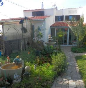 a garden in front of a house with a fountain at Casa das Palmeiras in Aljezur