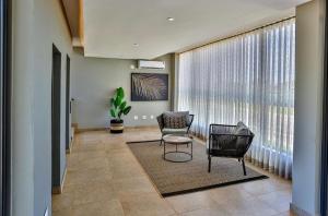 - un salon avec deux chaises, une table et une grande fenêtre dans l'établissement Zimbali Lakes Boulevard Suites 256, à Durban