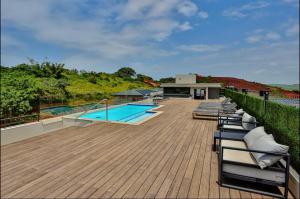 une terrasse avec des chaises longues et une piscine dans l'établissement Zimbali Lakes Boulevard Suites 256, à Durban