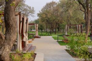 une passerelle dans un parc avec des bancs et des arbres dans l'établissement Radisson Blu Mosi-oa-Tunya Livingstone Resort, à Livingstone