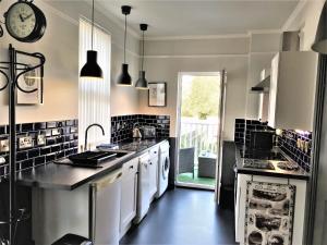 a kitchen with black and white appliances and a clock at Atlantis Holiday Apartments in Torquay