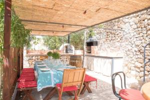 un patio con mesa, sillas y pared de piedra. en Villa Sol de Invierno - Deia en Deia
