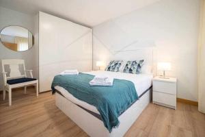 a white bedroom with a bed and a mirror at Ambar Playa San Lorenzo in Gijón