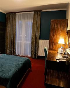 a hotel room with a bed and a desk and a window at Tenis Club in Kędzierzyn-Koźle