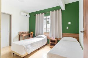 a bedroom with two beds and a green wall at Hotel Dom Rafael Express in Santa Maria