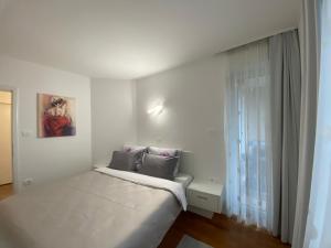 a white bedroom with a bed and a window at Apartments Villa BEAUTY PORTOROŽ in Portorož