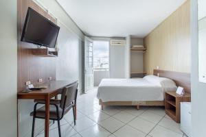 Habitación de hotel con cama, escritorio y TV. en Hotel Dom Rafael Express en Santa Maria