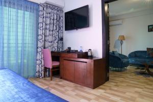 ein Hotelzimmer mit einem Schreibtisch und einem TV an der Wand in der Unterkunft Le Feto 2 in Dakar