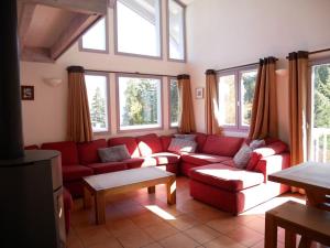 uma sala de estar com um sofá vermelho e janelas em Chalet Courchevel La Tania - 14 personnes - 7 chambres 7 salles de bains - 40 m des pistes em Courchevel