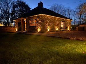 a stone house with lights in the yard at night at Dunromin Cottage, Hot Tub & Garden in Coxhoe