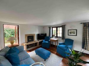 a living room with blue couches and a tv at Honeysuckle Cottage, Mickleton in Mickleton