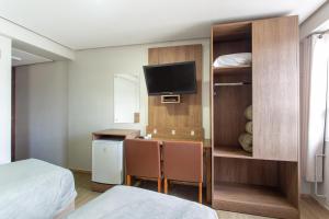 ein Hotelzimmer mit einem Bett und einem Schreibtisch mit zwei Stühlen in der Unterkunft Hotel Dom Rafael Executivo in Santa Maria