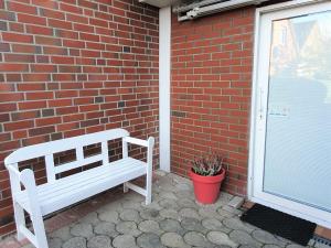 um banco branco sentado ao lado de uma parede de tijolos em Apartment Nordseeblick em Norddeich