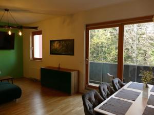 a living room with a table and chairs and a large window at Forest Green Pohorje Apartment in Hočko Pohorje
