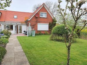 a house with a green yard with a tree at Ferienhaus Nordseeblick in Norddeich