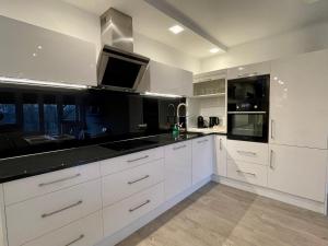 a kitchen with white cabinets and a black counter top at Nowoczesny Apartament z widokiem na rzekę i jezioro in Ełk