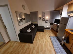 uma sala de estar com um sofá preto e um frigorífico em Bellyenmer Gruissan em Gruissan