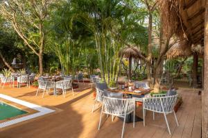 a patio with tables and chairs next to a pool at Larisa Resort Ashwem in Mandrem